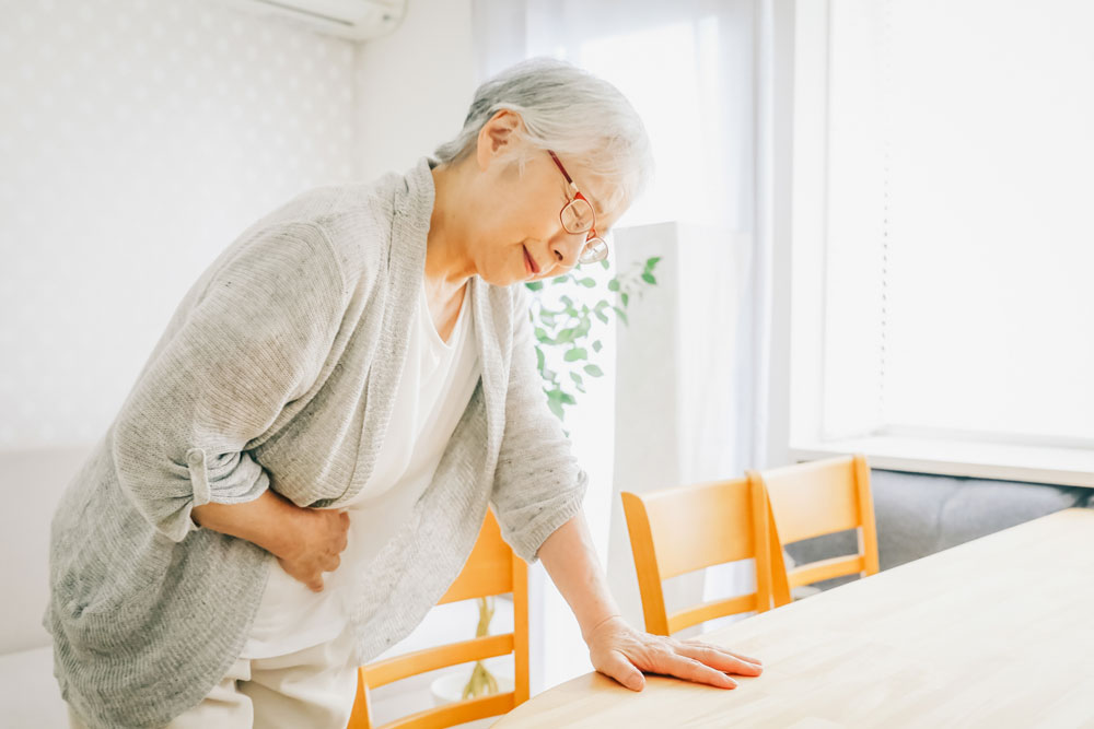 食中毒でお腹をおさえる女性