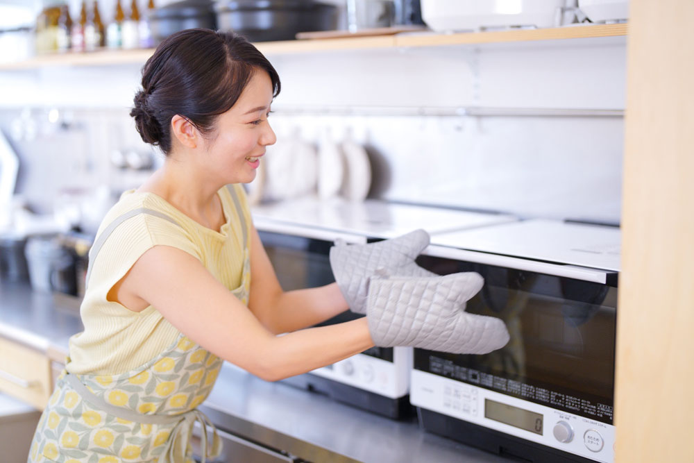 オーブンを開けようとしている女性